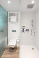 Ein modernes Badezimmer mit Duschkabine aus Glas, Toilette und Duschkopf.