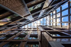 A modern building with multiple floors, large windows, and a complex roof structure.