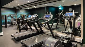 A gym with treadmills, exercise machines, and a mirrored wall.