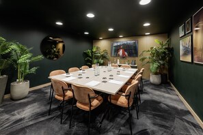 A conference room with a long table, chairs, and potted plants. - Yotel London City (London)