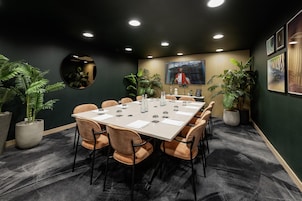 Una sala conferenze con un lungo tavolo, sedie e piante in vaso.
