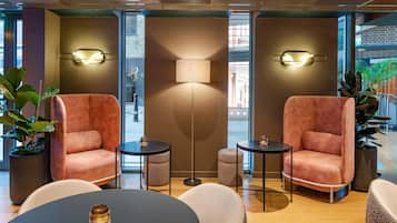 A modern lounge area with two plush armchairs, a floor lamp, and a round table with a candle.