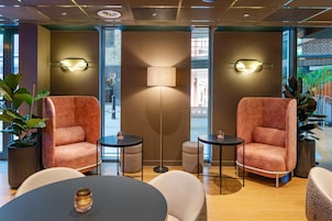 Eine moderne Lounge-Ecke mit zwei bequemen Sesseln, einer Stehlampe und einem runden Tisch mit Kerze.