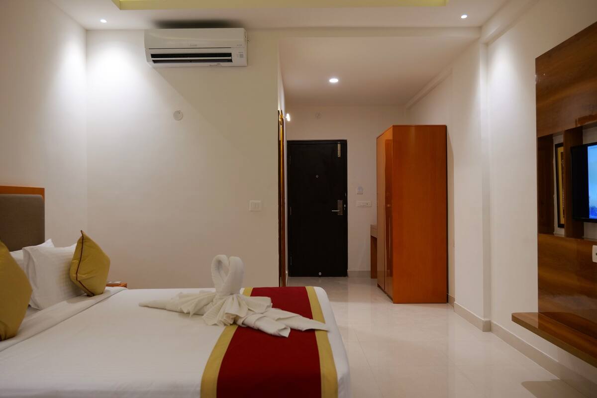 Habitación de hotel con cama, almohadas, bata, equipo de aire acondicionado, televisor y panel de madera en la pared.