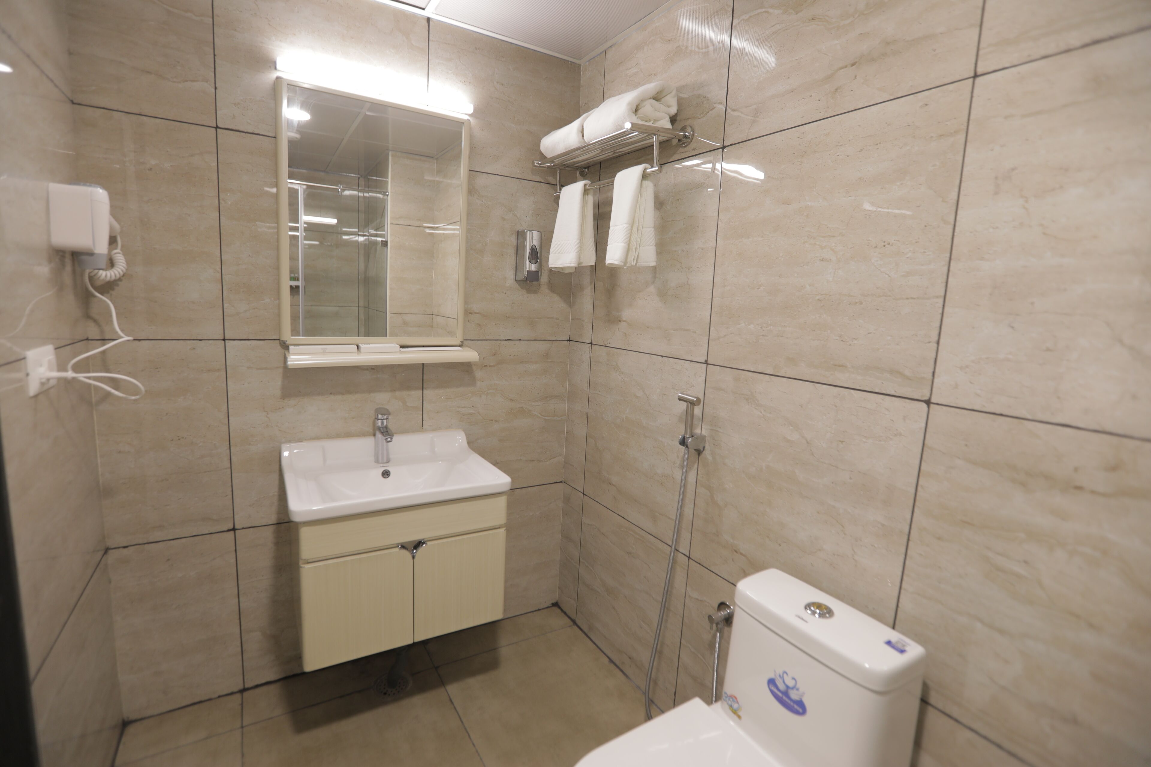 Un baño con lavamanos, espejo, toallero y retrete.