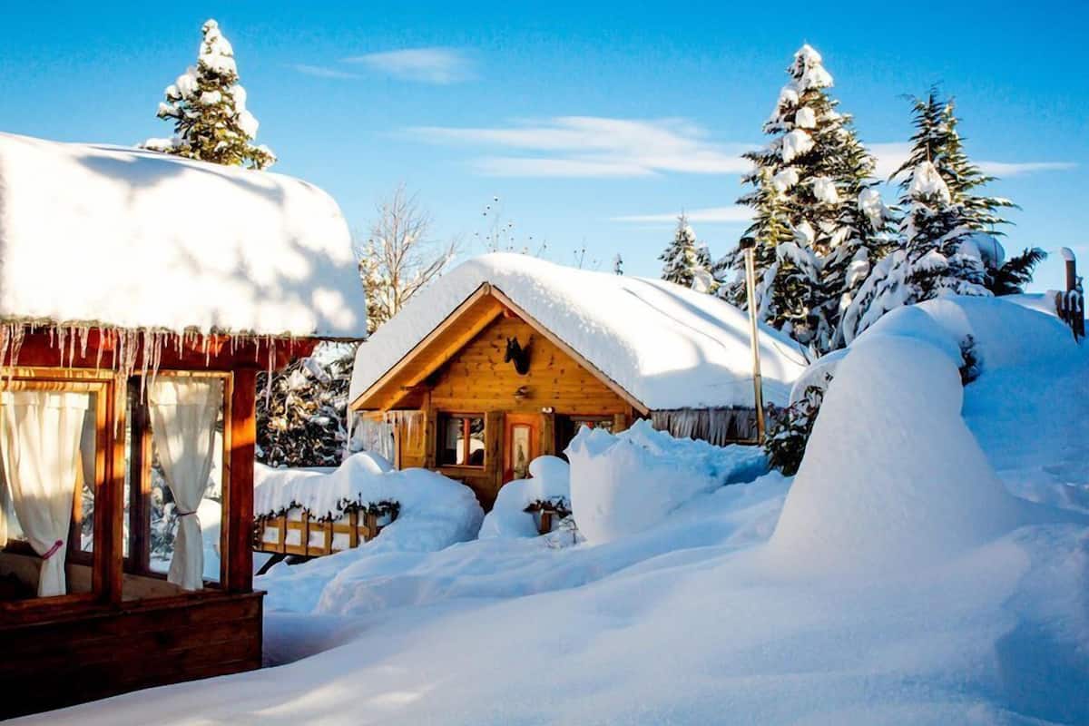Eine Holzhütte, umgeben von schneebedeckten Bäumen.