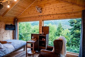 Una habitación de cabaña de madera con cama, escritorio, silla y televisor.