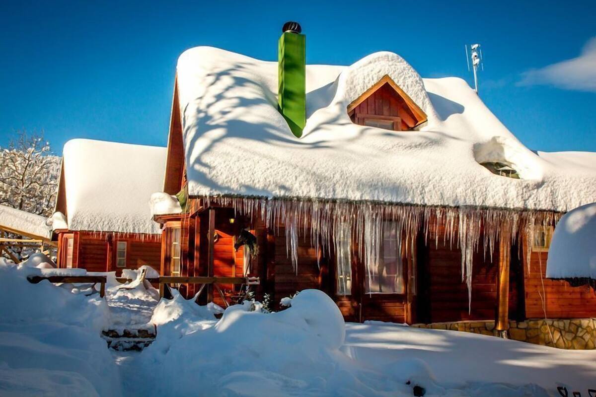 Eine Holzhütte mit schneebedecktem Dach und Eiszapfen an den Dachvorsprüngen.
