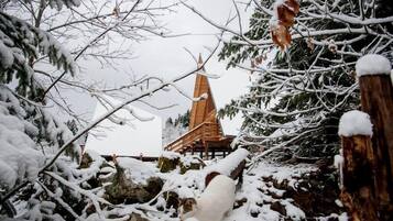 A snow-covered landscape with a wooden structure in the background.