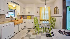 Una cucina con pensili bianchi, un piano di lavoro in legno, un lavello, un fornello e un tavolo da pranzo con sedie.