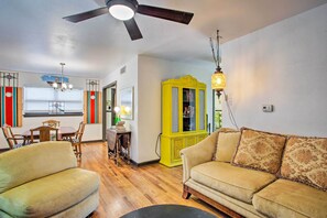 Uma sala de estar com um ventilador de teto, um armário amarelo e um sofá bege.