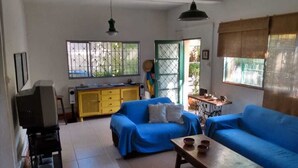 A living room with two blue sofas, a wooden coffee table, a yellow cabinet, and a television on a stand.