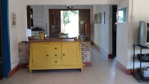 A spacious kitchen with a yellow island, a view of the outdoors, and a dining area with chairs.