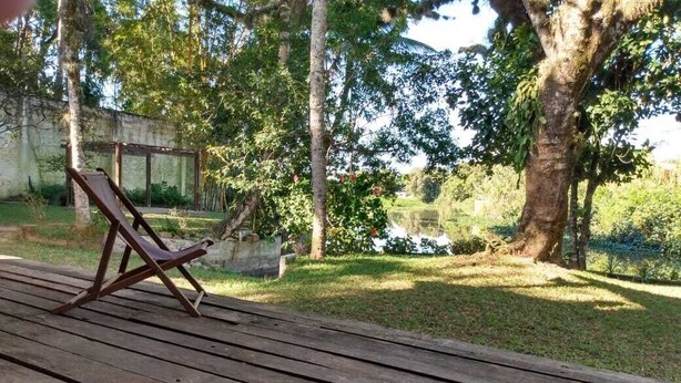 A wooden deck with a pair of lounge chairs and a small pond in the background.