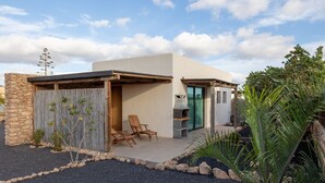 Una casa moderna con un patio, zona de barbacoa y una pared de piedra.