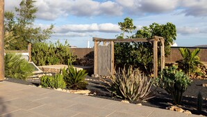 Un jardín con un pérgola de madera, varios cactus y suculentas.