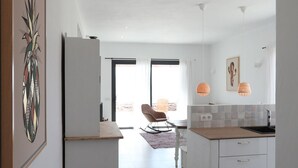 Cocina amplia con isla central, armarios blancos e iluminación colgante.
