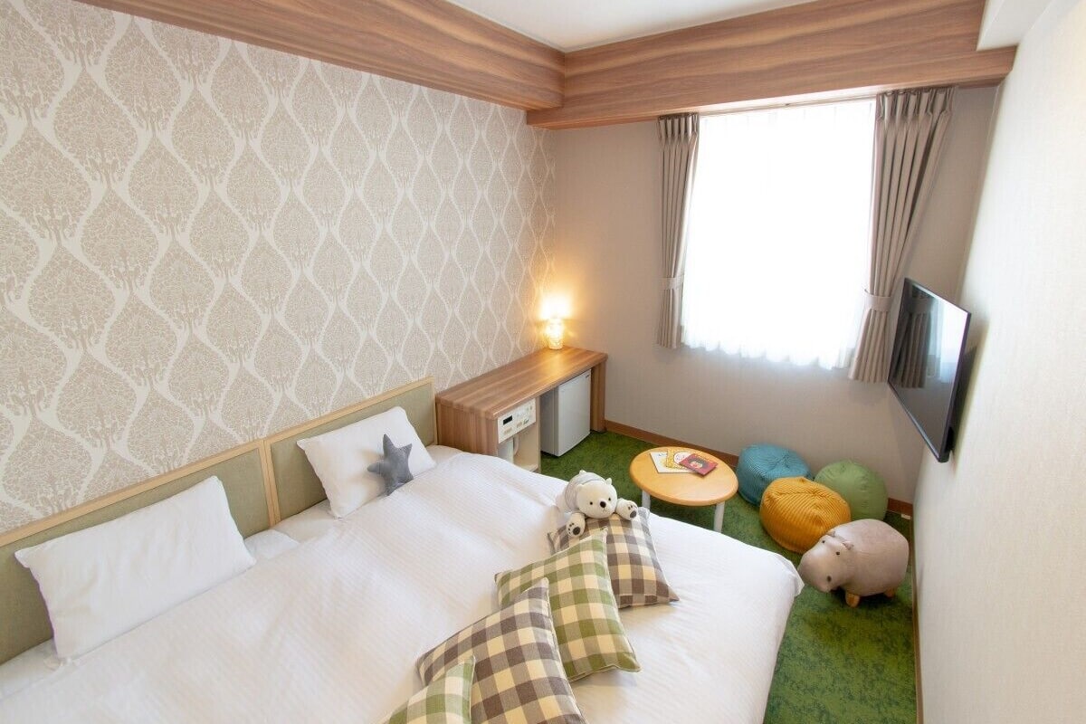 Une chambre d’hôtel avec un grand lit, une table de chevet, une petite télévision et une fenêtre avec des rideaux.