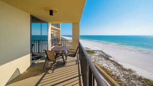 A balcony with a table and chairs overlooking a beach. - **WEEKLY SPECIALS!** Phoenix II - 7th Floor - 2 Bedroom (Orange Beach)