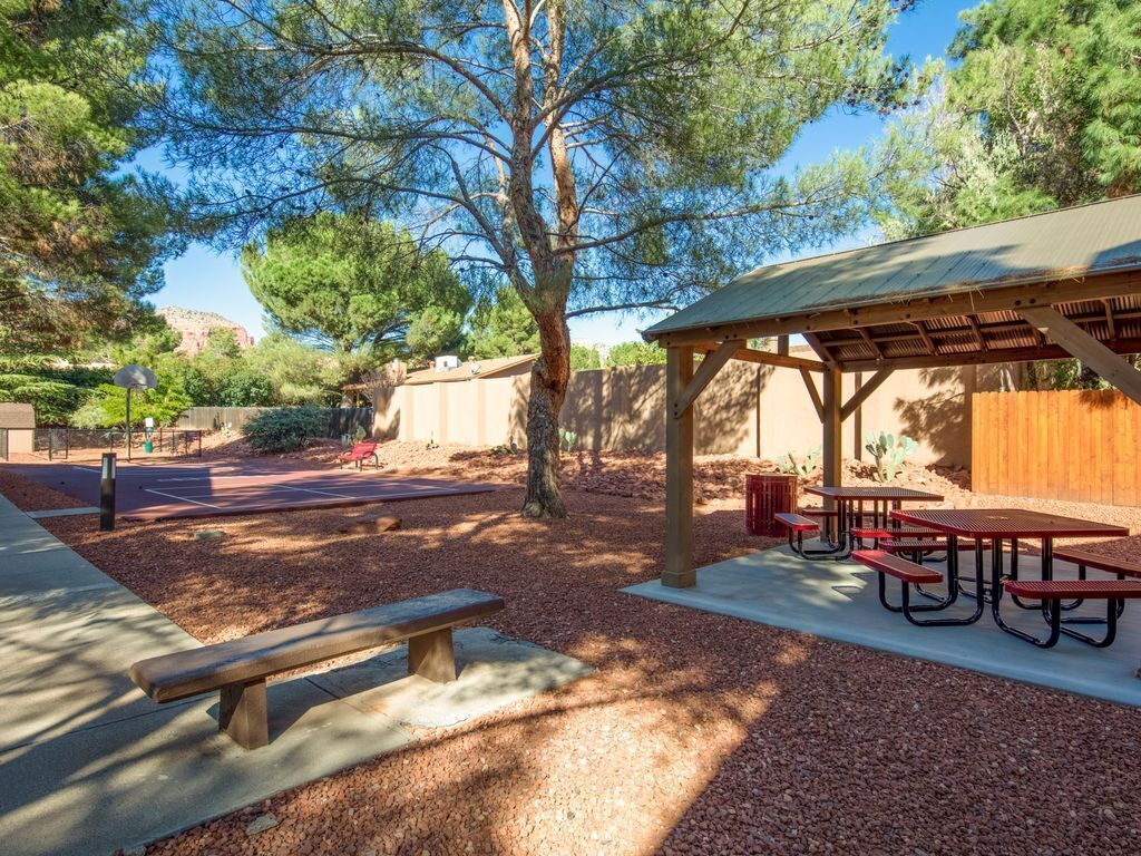 Un patio al aire libre con mesas de picnic y una zona de estar cubierta.