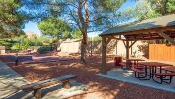 Un patio al aire libre con mesas de picnic y una zona de estar cubierta.