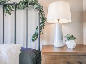 A bed with a white blanket, a bedside table with a lamp, and a small potted plant. - Stylish Sedona Condo | Red Rock Views, Modern Comfort & Quiet Location (Sedona)