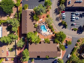 An aerial view of a parking lot with multiple cars, a landscaped area with a pool, and surrounding buildings. - Stylish Sedona Condo | Red Rock Views, Modern Comfort & Quiet Location (Sedona)