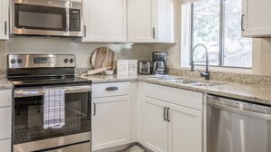 A modern kitchen with white cabinets, stainless steel appliances, a granite countertop, and a window with a view. - Stylish Sedona Condo | Red Rock Views, Modern Comfort & Quiet Location (Sedona)