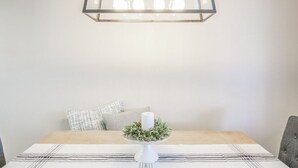 A dining table with a white candle centerpiece, a patterned table runner, and a modern pendant light fixture above. - Stylish Sedona Condo | Red Rock Views, Modern Comfort & Quiet Location (Sedona)