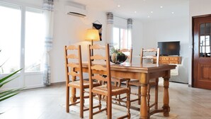 Un comedor con una mesa y sillas de madera, una lámpara y un televisor al fondo.