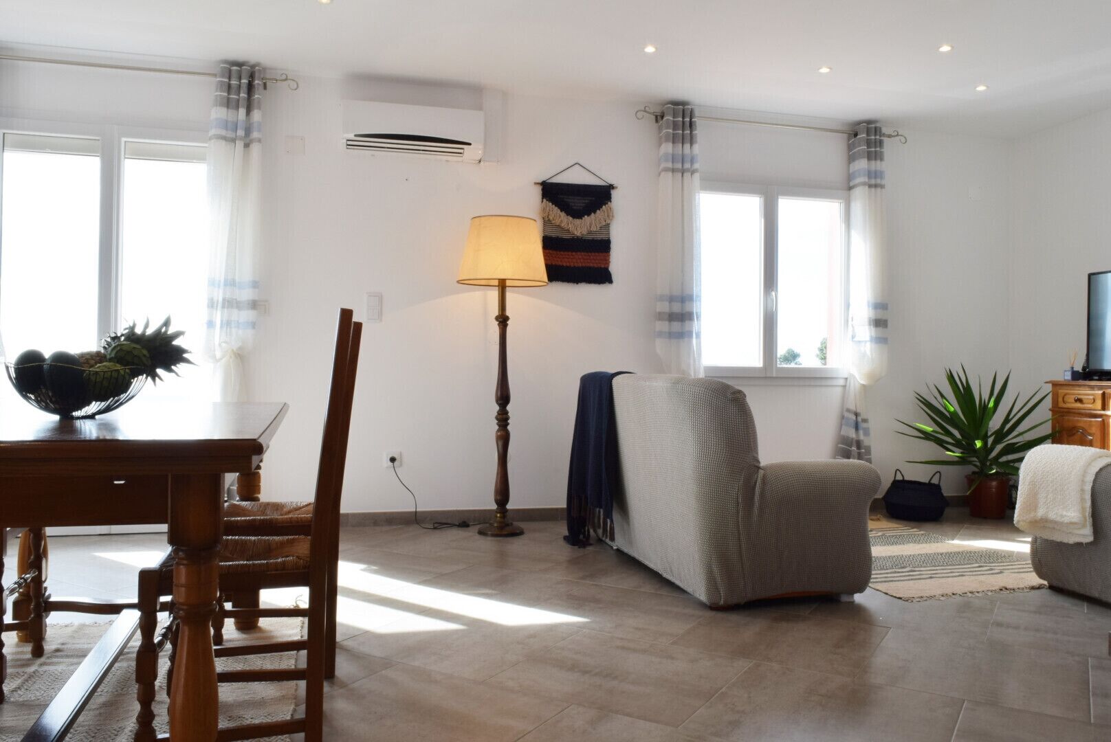 A living room with a dining table, a sofa, a lamp, and a television.