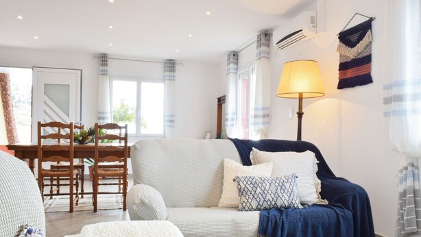 Una sala de estar con sofá, sillones, una mesa de comedor con sillas y una lámpara.
