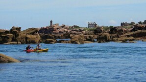 A rocky coastline with a lighthouse and a building in the background.