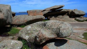 Large boulders with a clear sky and ocean in the background.