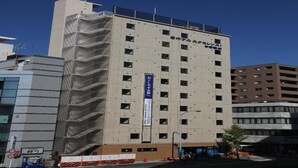 Un immeuble à étages doté d’une architecture moderne, caractérisé par une série de fenêtres et une enseigne verticale bien visible.