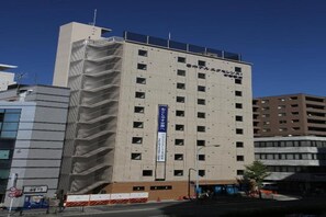 Un immeuble à étages doté d’une architecture moderne, caractérisé par une série de fenêtres et une enseigne verticale bien visible.