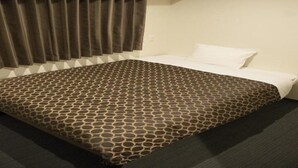 Une chambre d’hôtel avec une couvre-lit à motifs, une grande fenêtre avec des rideaux et un sol recouvert de moquette.