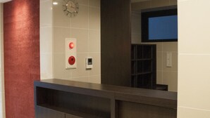 A reception desk with a clock, a red emergency button, and a digital screen.