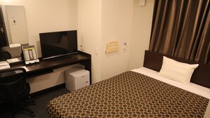 A hotel room with a bed, a desk with a computer, a television, and a small refrigerator.
