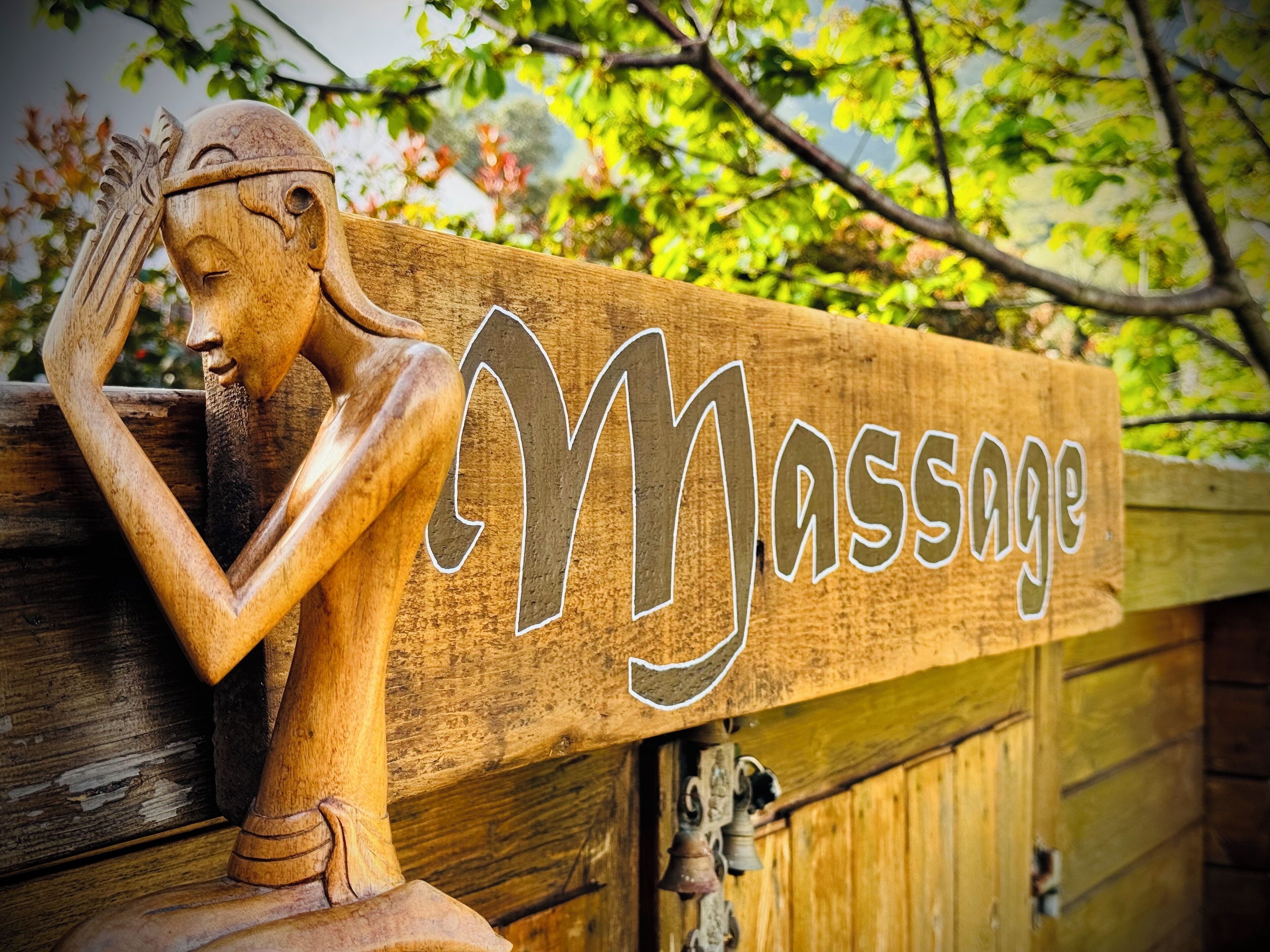 A wooden sign with the word "Massage" and a wooden sculpture of a woman.