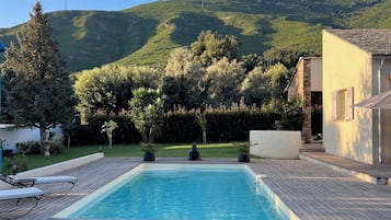 Una piscina al aire libre de temporada, sombrillas, tumbonas