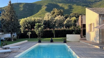 Una piscina al aire libre de temporada, sombrillas