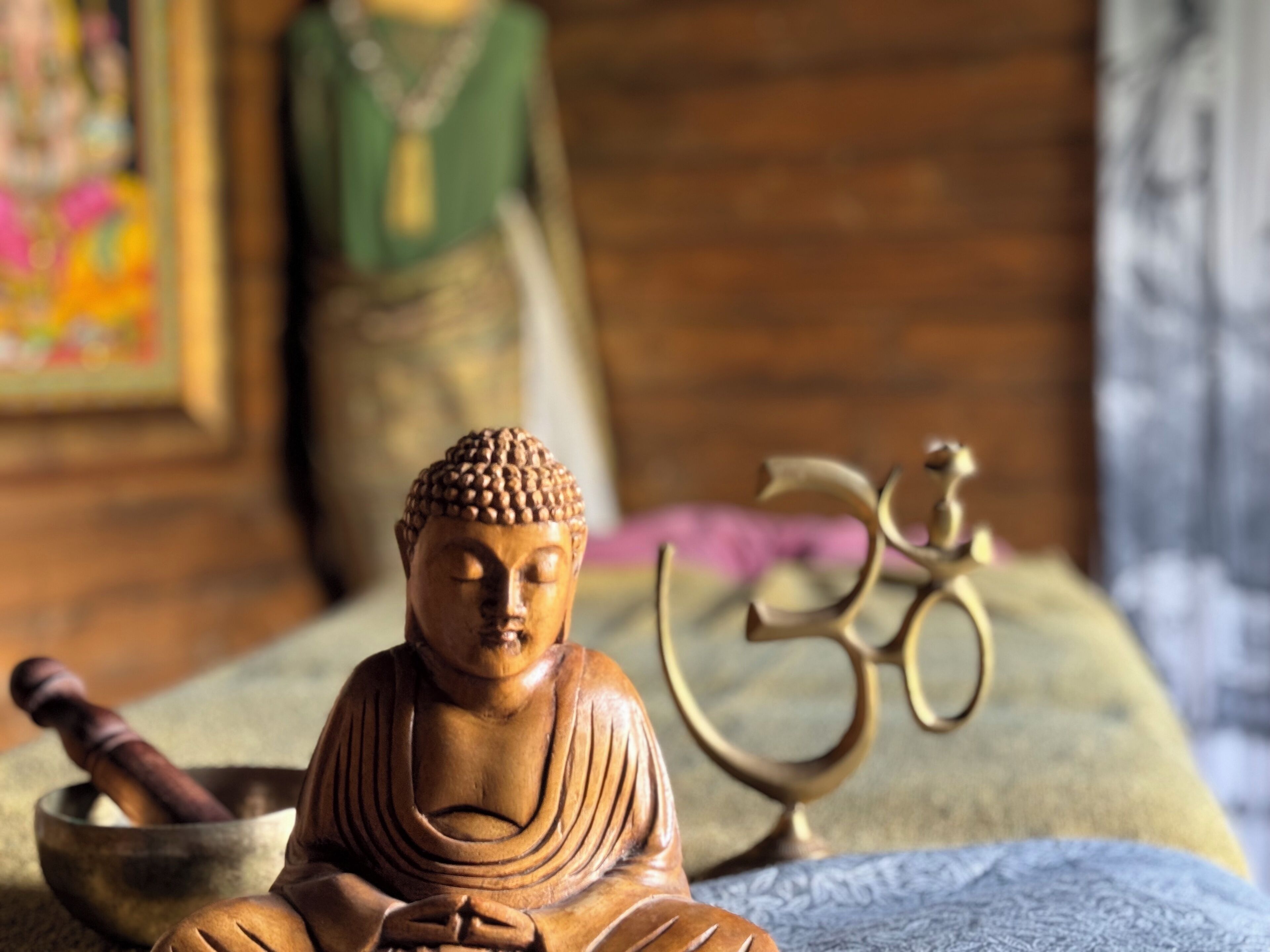Una estatua de Buda de madera, un cuenco de meditación y el símbolo de Om.