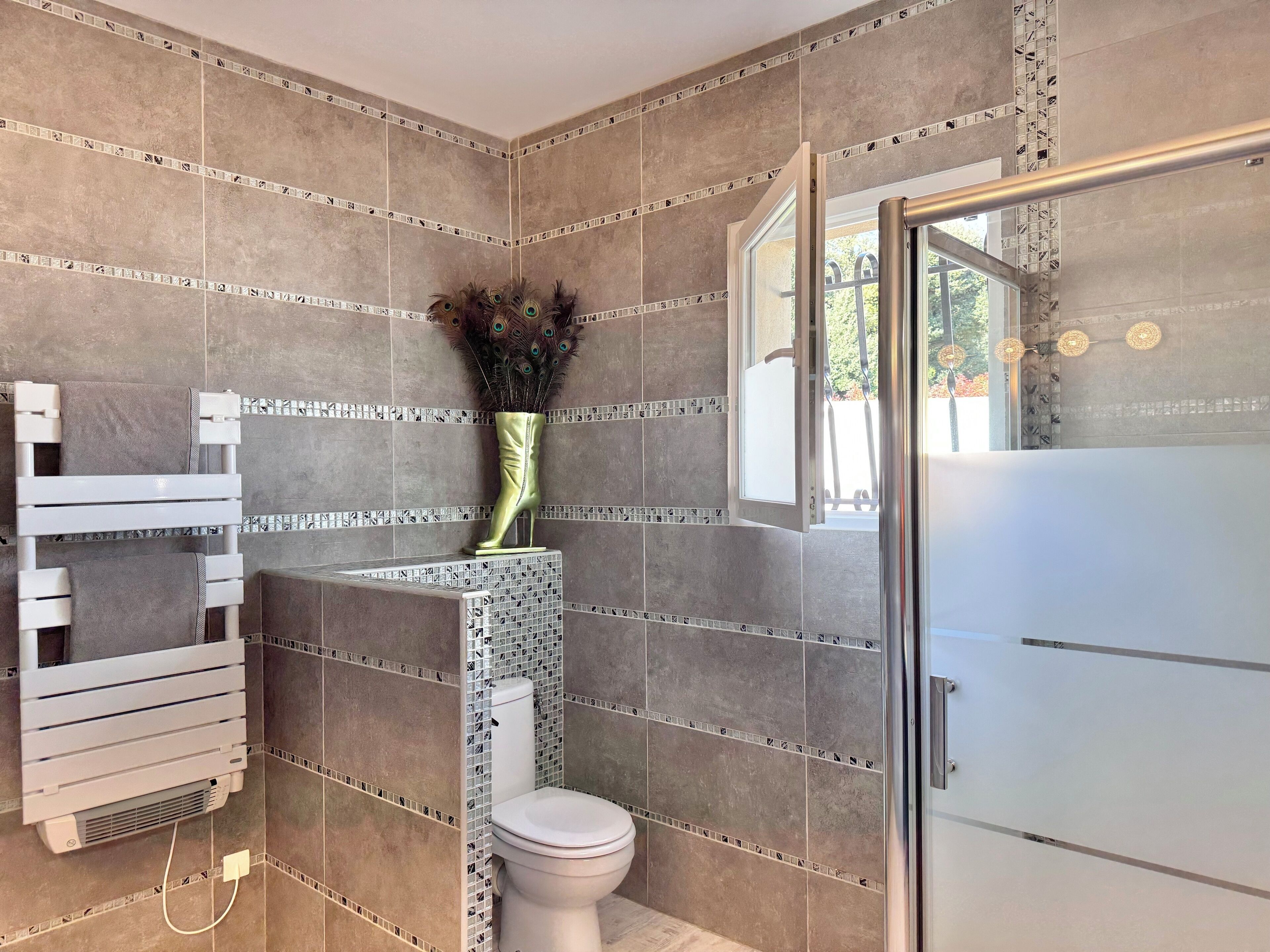 A bathroom with a toilet, a shower area, and a vanity with a mirror.