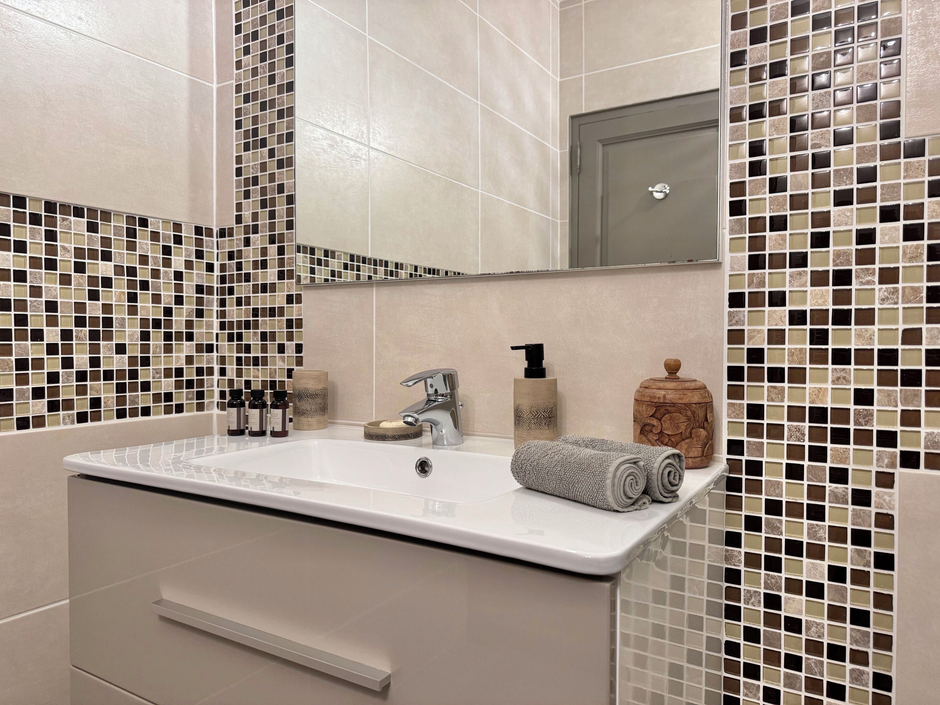 A bathroom with a white sink, a mirror, and tiled walls.