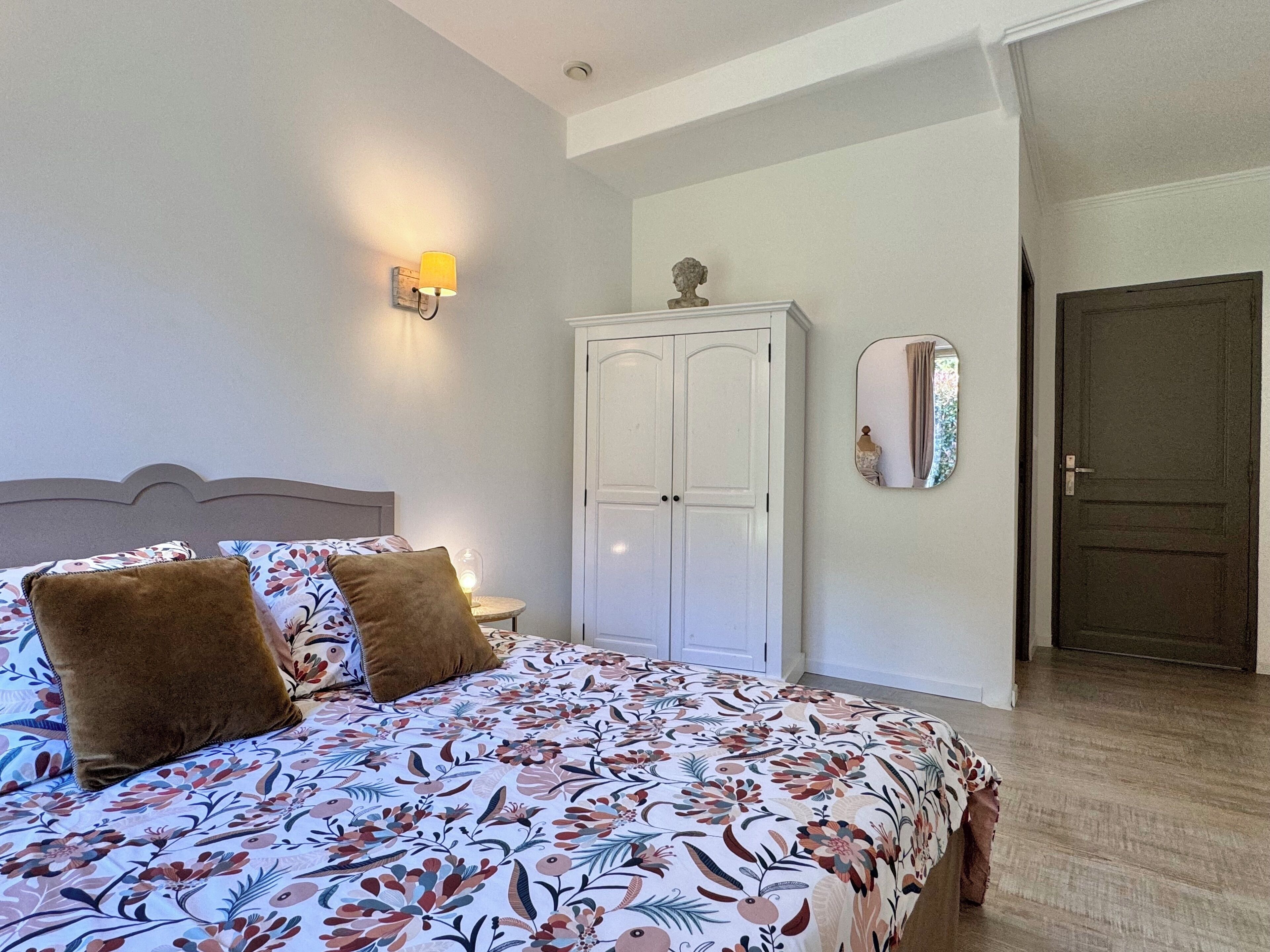 Un dormitorio con cama, armario, espejo y puerta.