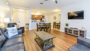 A modern living room with a sofa, a coffee table, and a dining area with chairs and a table. - 2 Bed Room Premium [cdc Compliant] l 2005 (Orlando)