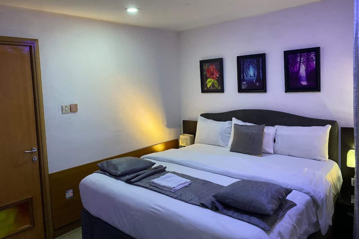 A hotel room with a double bed, two bedside tables, and three framed pictures on the wall.