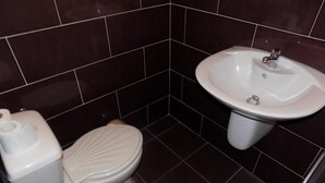 A bathroom with a toilet, sink, and dark tiled walls. - Krystal Park studio in Sunny Beach (Sonnenstrand)