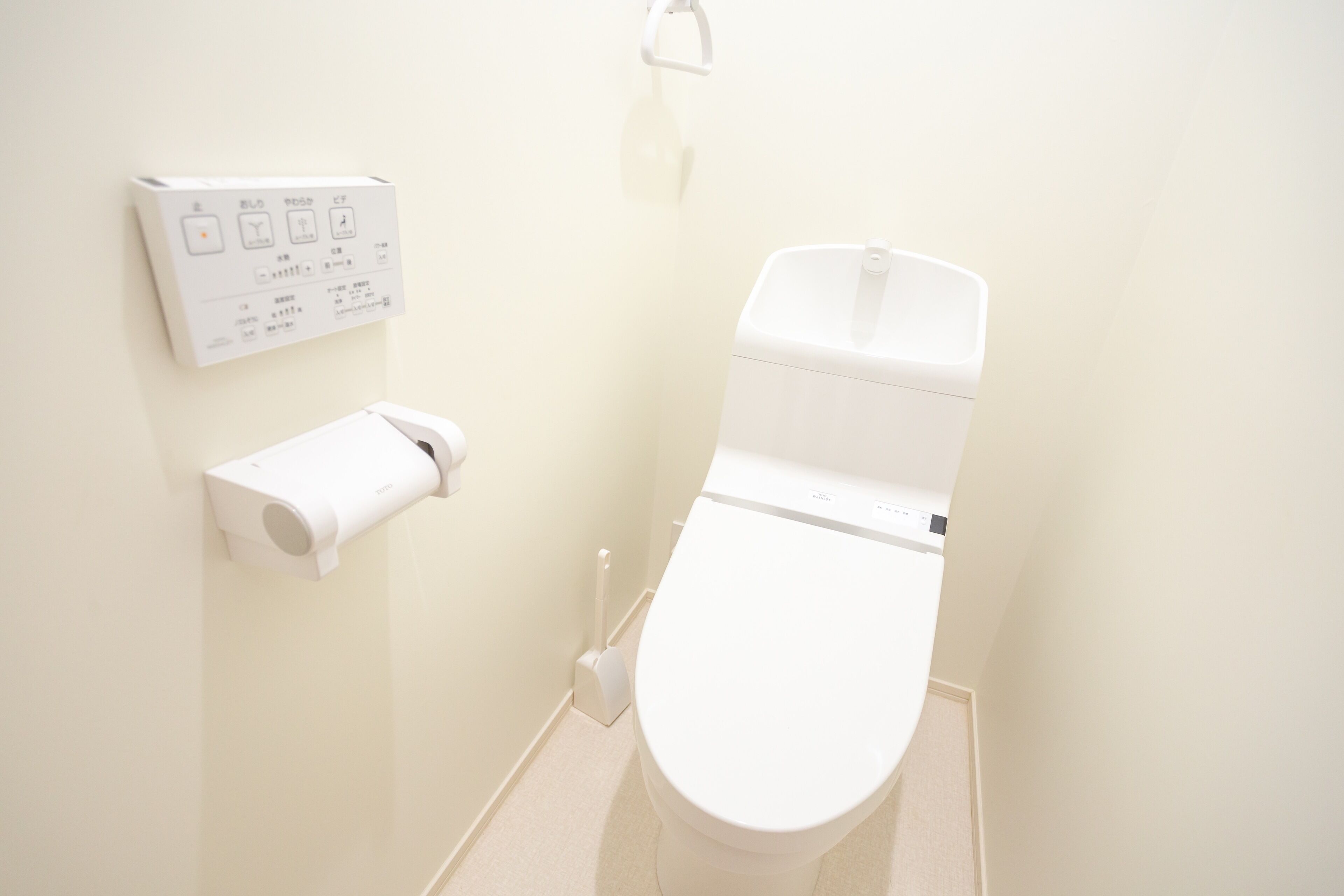 Un baño pequeño y limpio con inodoro, soporte para papel higiénico y panel de control para bidé.